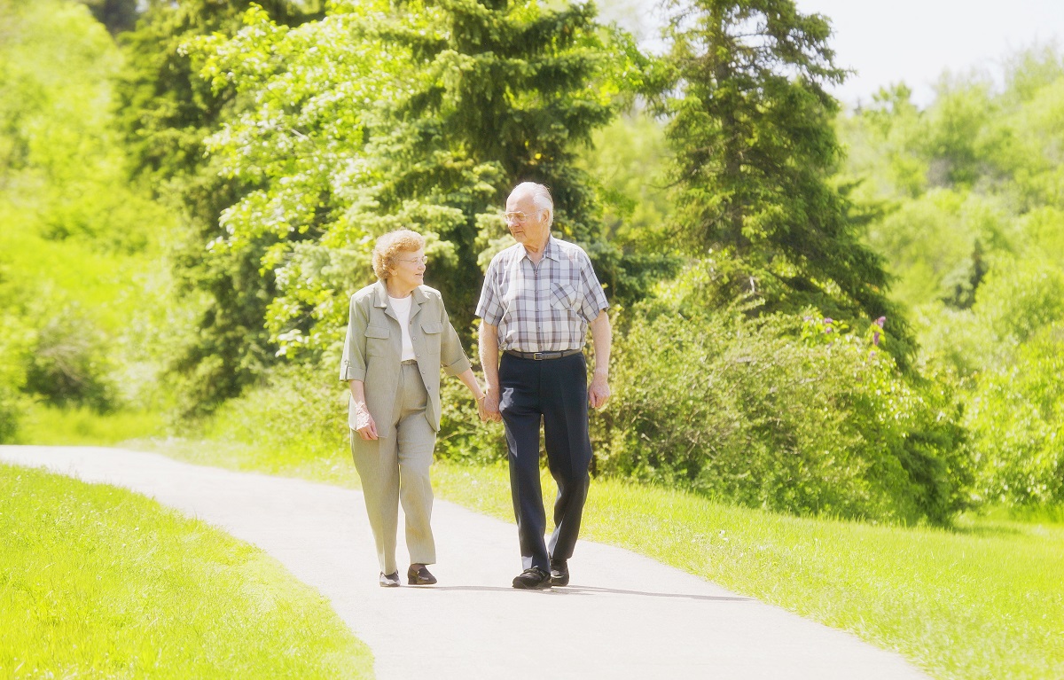 an elderly couple walking hand in hand outside