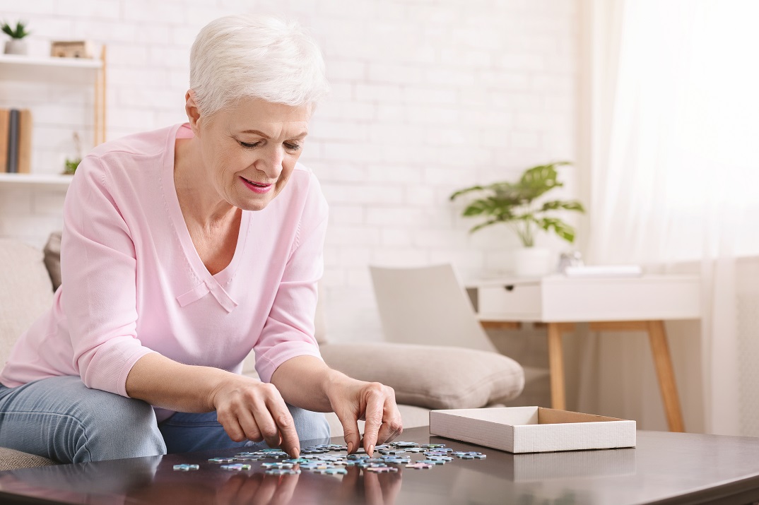 woman piecing together jigsaw puzzle.