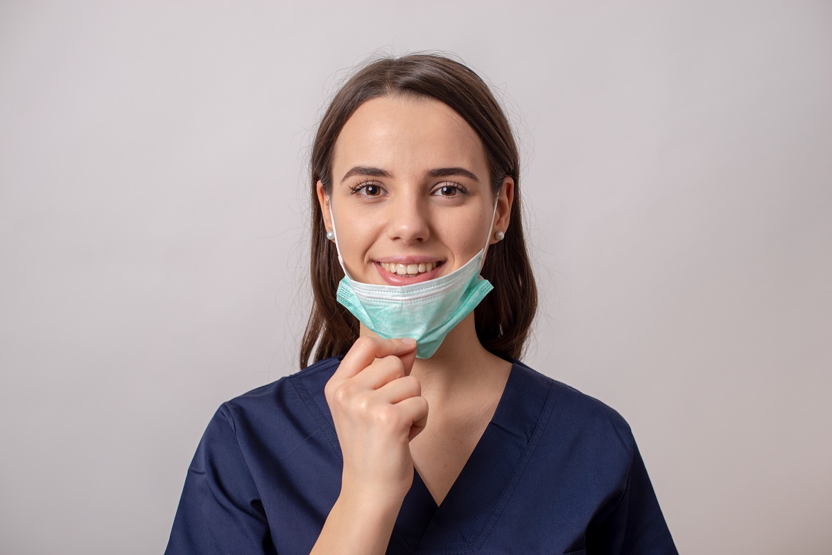 Doctor woman smiling, removing her mask because Covid pandemic is over