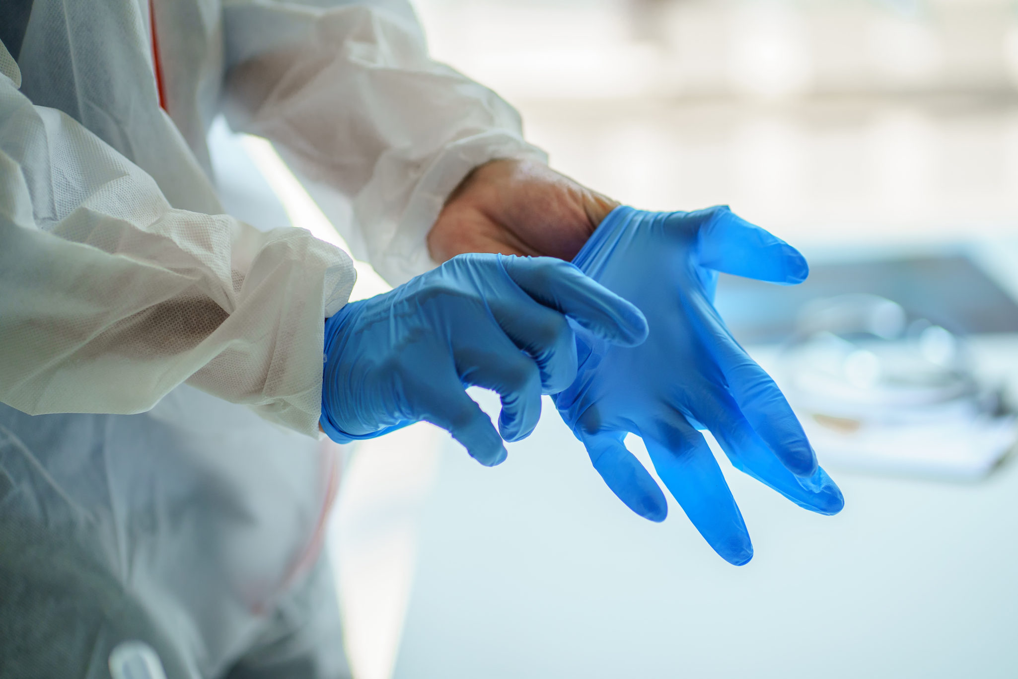 a healthcare worker putting on medical gloves for protection