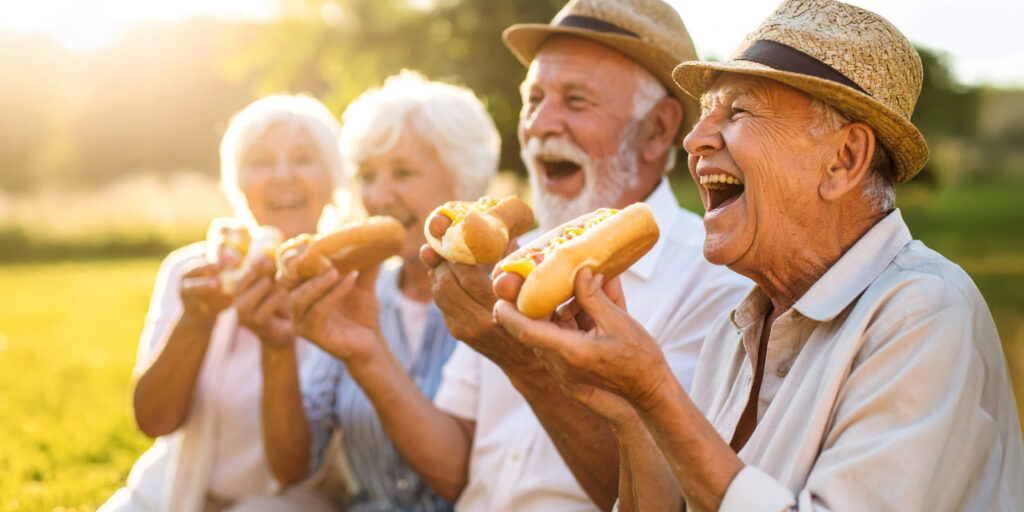 Four seniors enjoying hotdogs at The Glebe July event